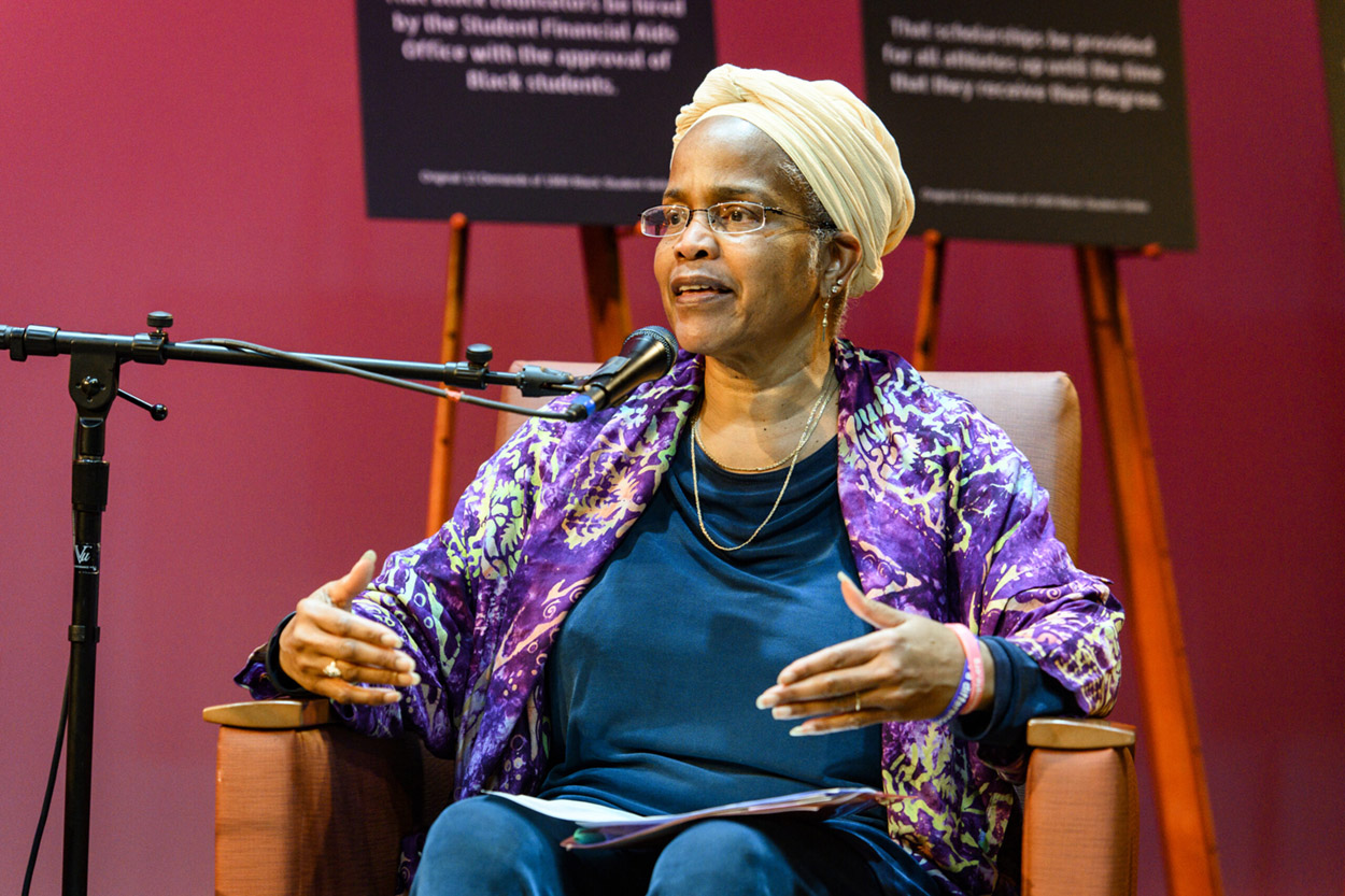 Hazel sitting on a stage speaking into a microphone.